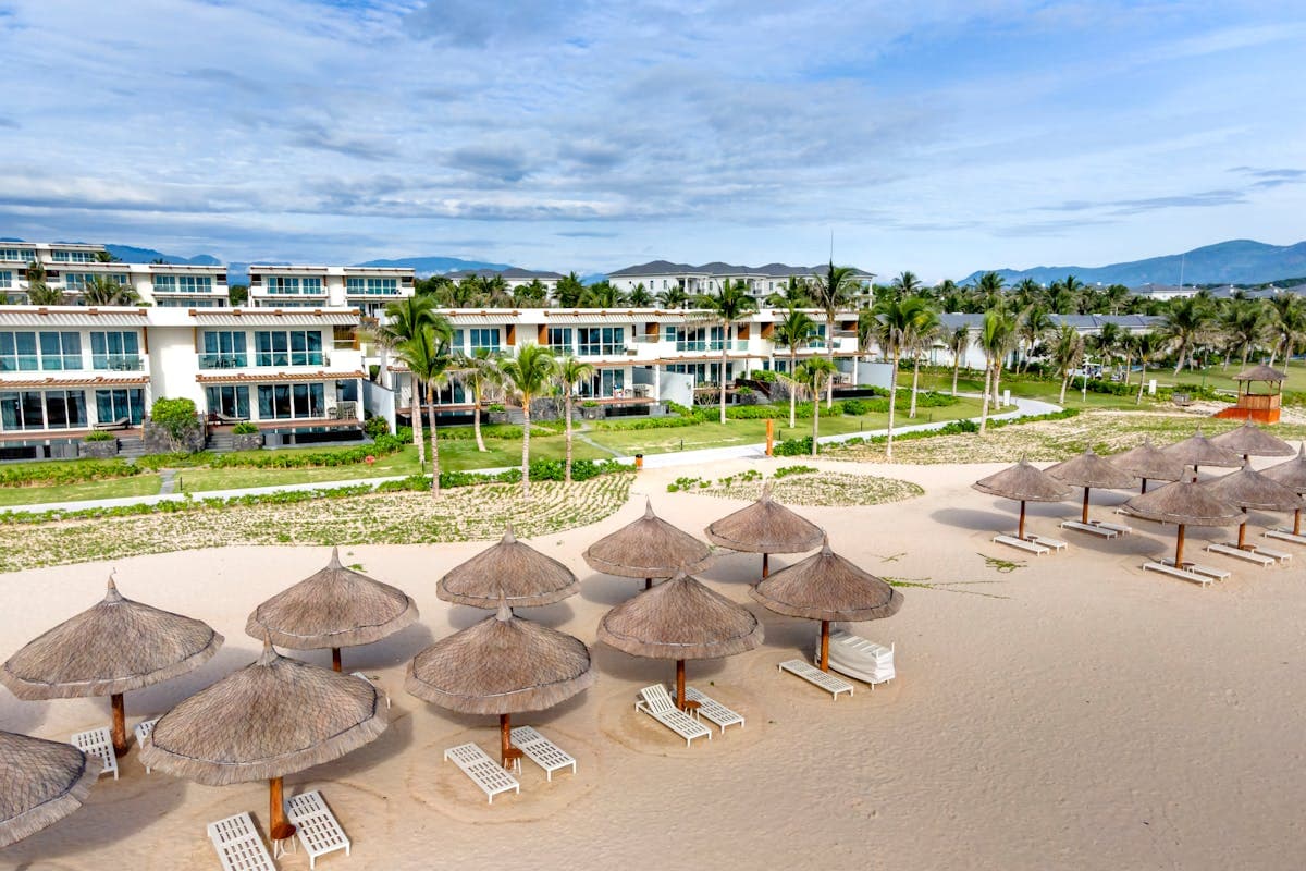 Sun loungers and palm-shaded beachfront restaurants on the sand at An Bang Beach near Hoi An