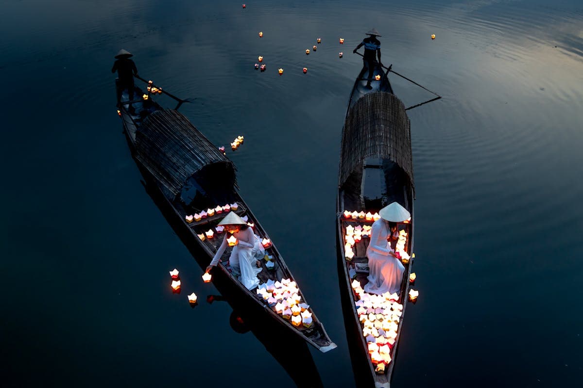 Floating paper candle boats glowing on the Thu Bon River at night in Hoi An