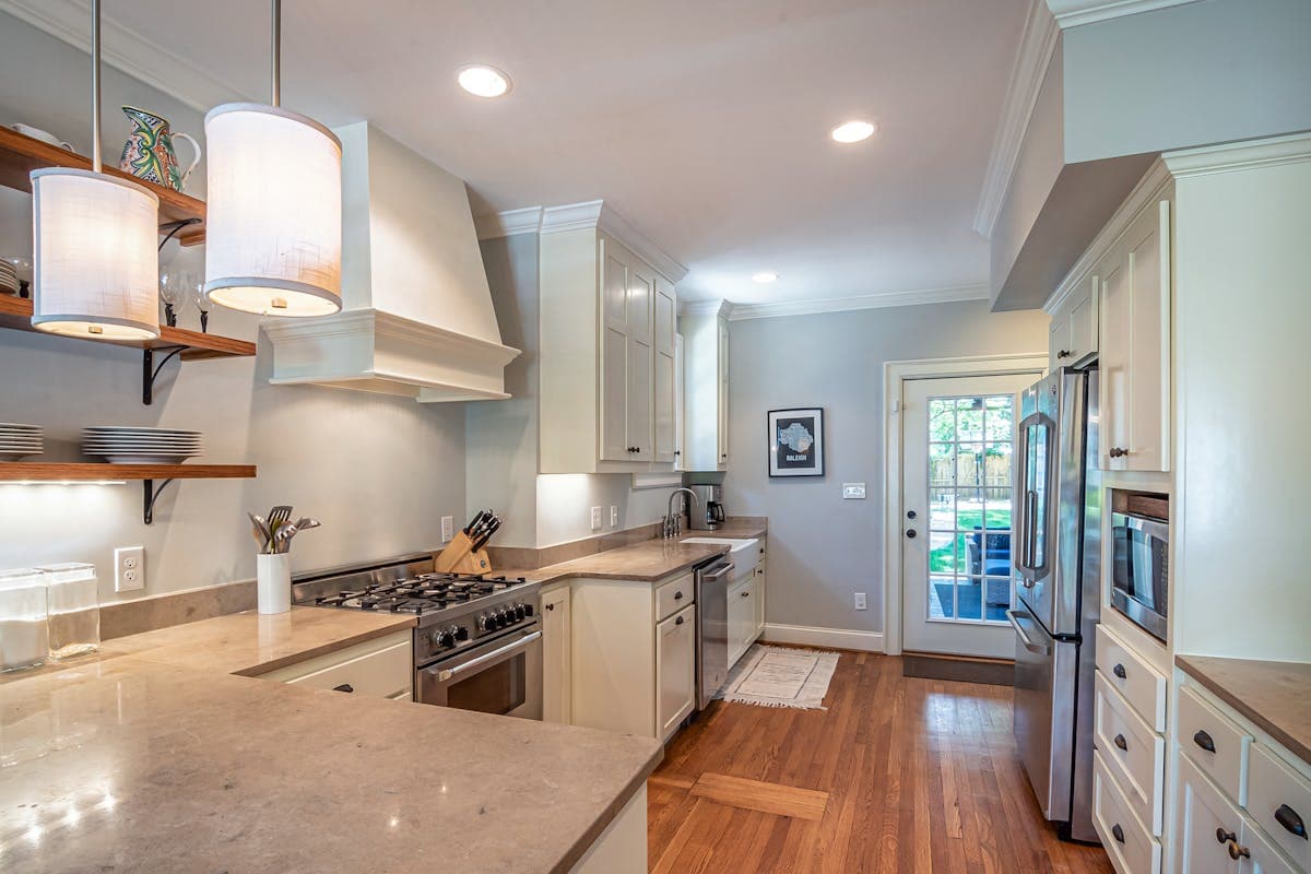 Stylish modern kitchen with matching cookware, upgraded utensils and quality glassware on open shelves