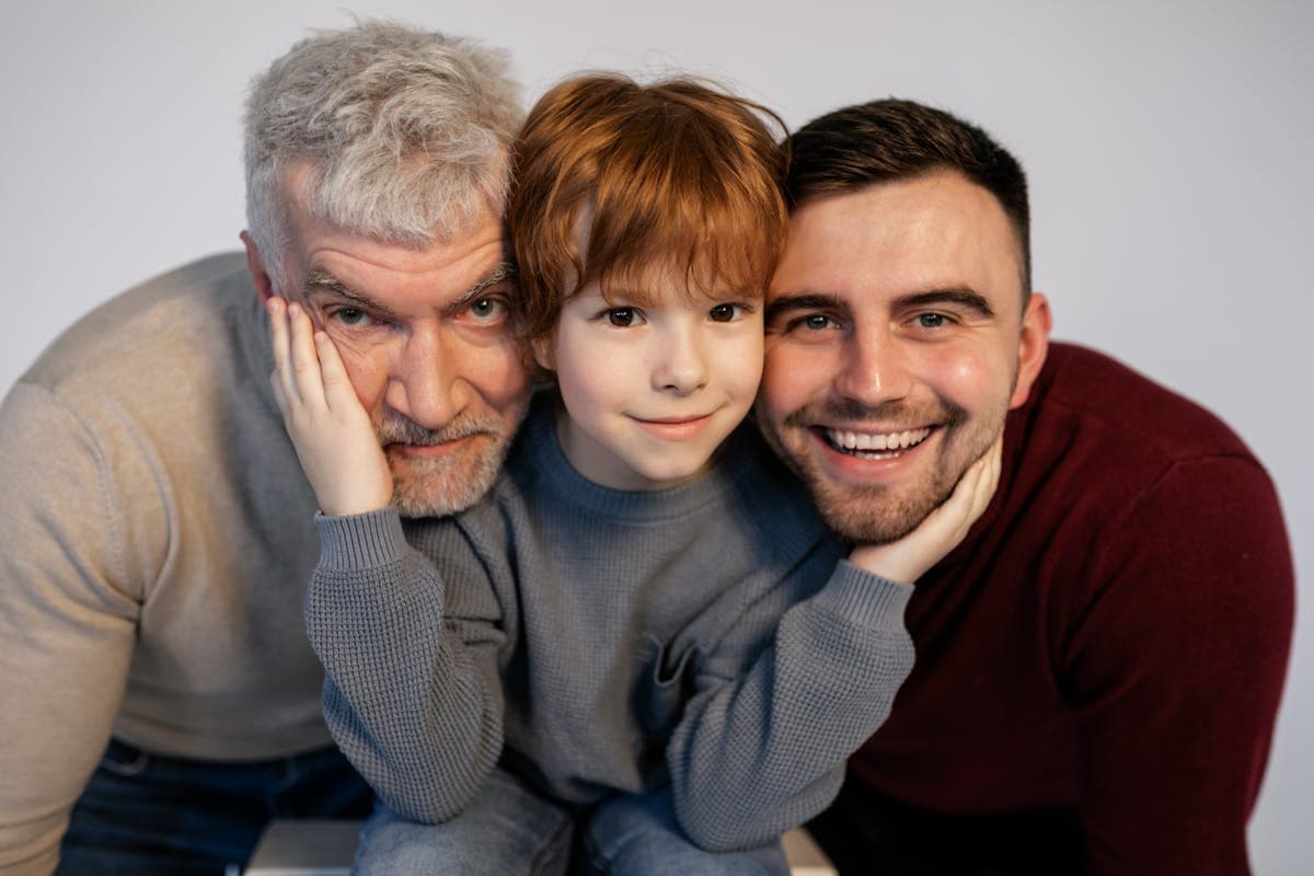 Grandfather, father and young teenage boy standing together in dark suits for a family photograph
