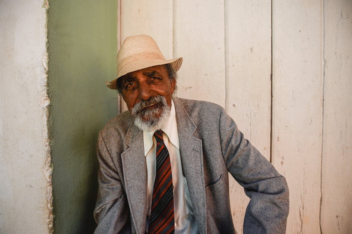 Man in a light stone summer suit and Panama straw hat with a knit tie, the traditional clubhouse look for Saratoga
