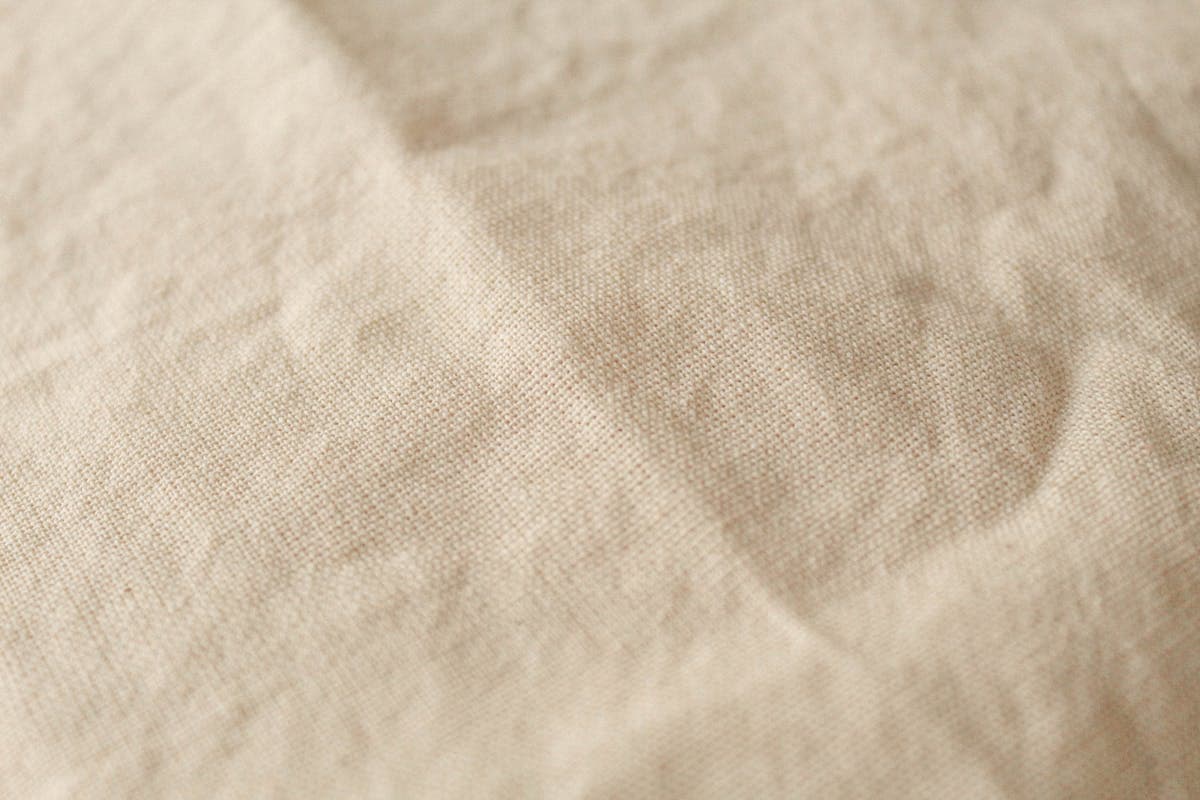 Close-up of breathable summer-weight linen and lightweight wool suiting fabric in stone and sand tones