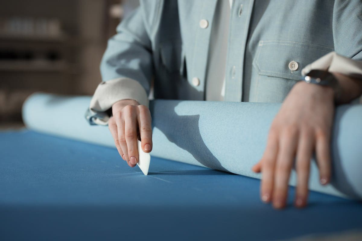 Tailor's hands marking tailor's chalk on light summer-weight suit cloth on a workbench with measuring tape and shears