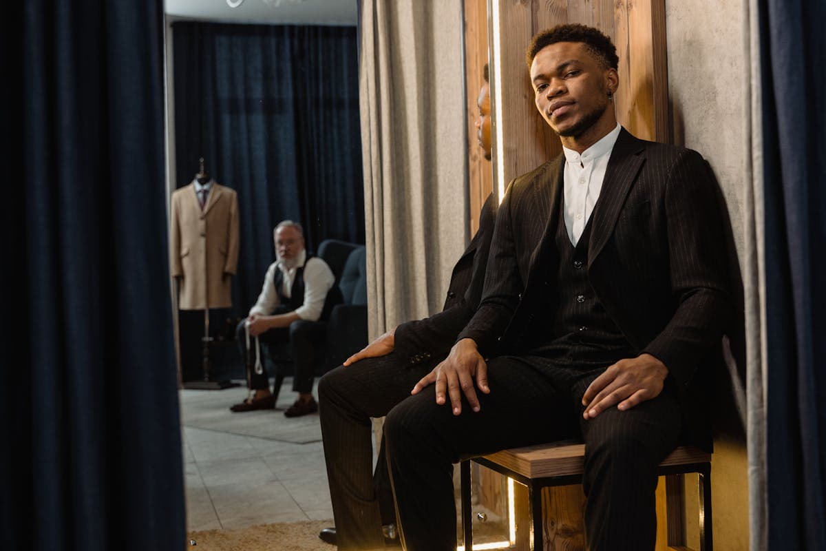 Man in a well-fitted suit checking the jacket fit in a tailor's fitting-room mirror
