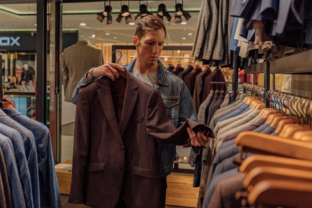 Rows of identical off-the-rack suits hanging in standard sizes on a retail clothing rack