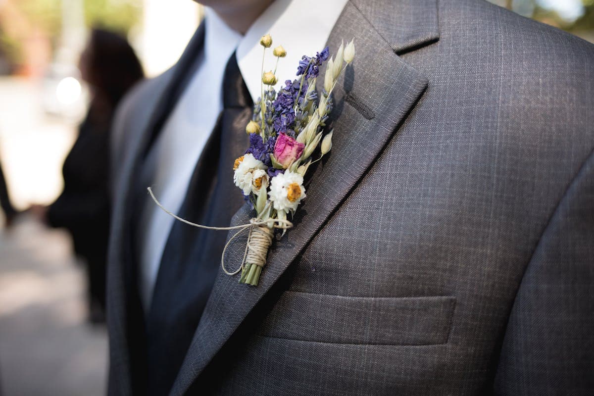 Man in a light linen suit at an outdoor summer garden wedding, relaxed and weather-appropriate in warm sunshine