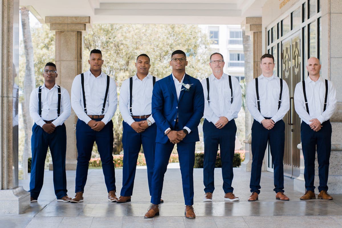 Groom in burgundy standing with a wedding party in coordinated sage and dusty rose tones, showing how the color reads as intentional