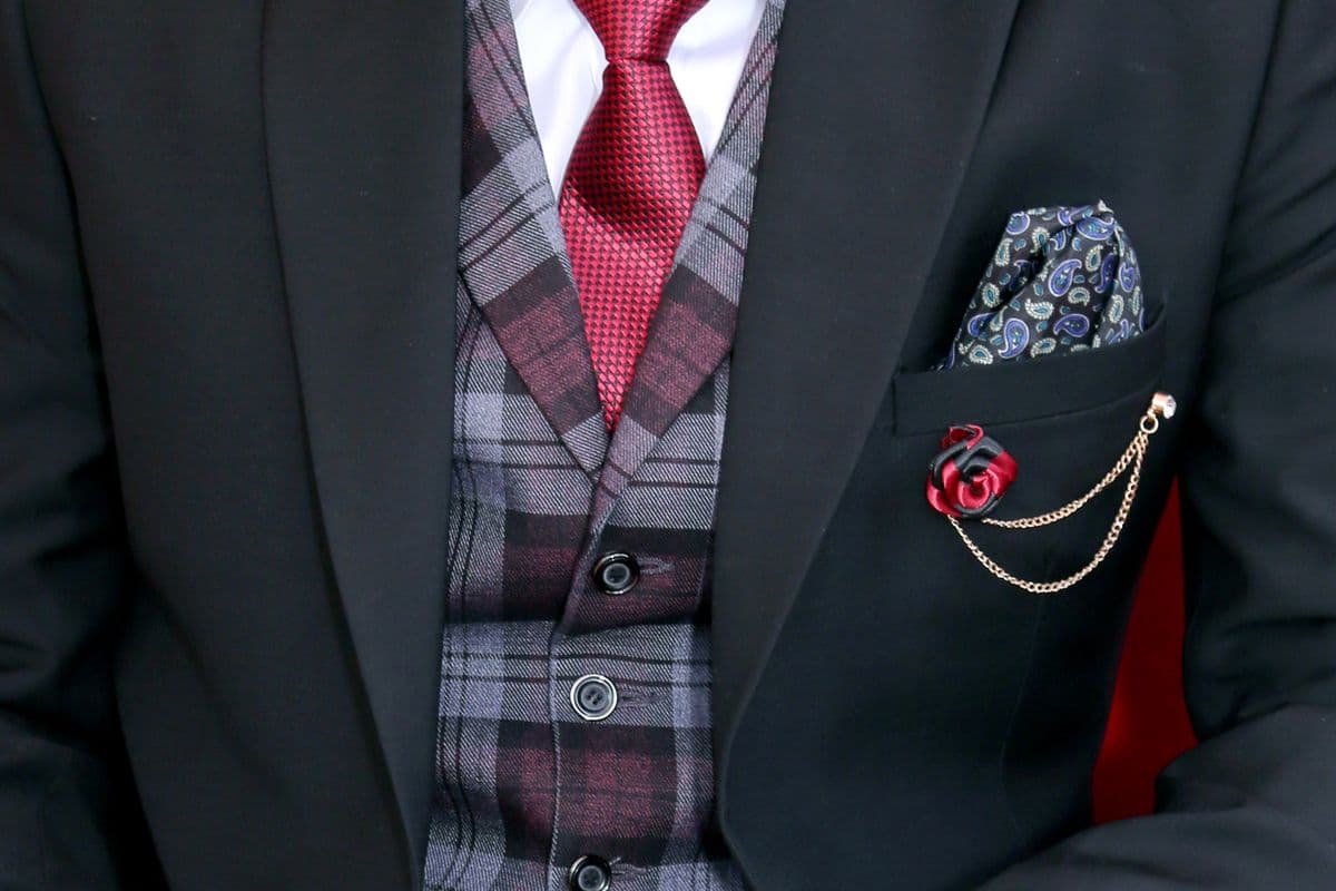Groom in a merlot three-piece suit with waistcoat photographed in soft daytime garden light