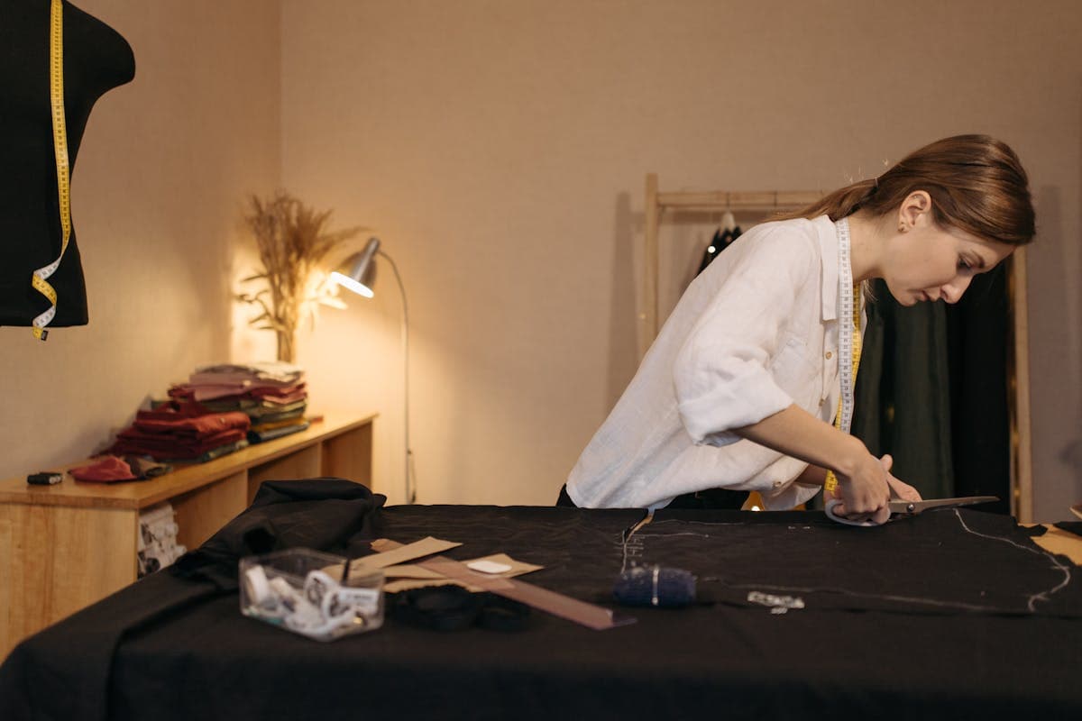 Tailor's hands cutting wool suiting cloth with shears on a workshop table