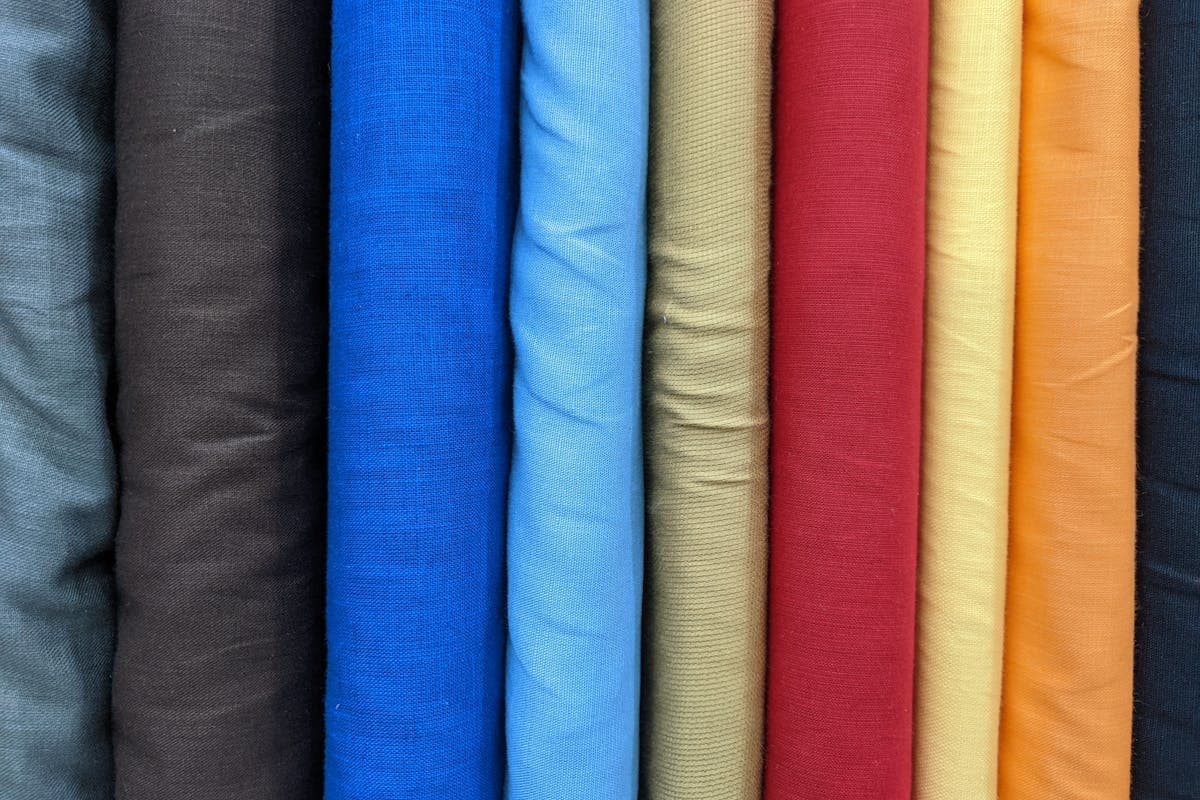 Stacked bolts and swatches of wool suiting fabric in different colors and weaves