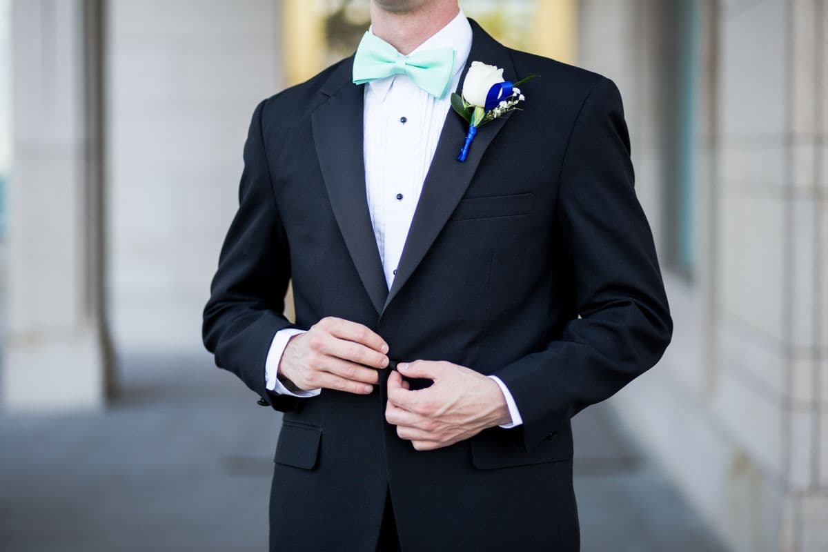 Man in a midnight blue peak-lapel tuxedo with black bow tie in low evening light
