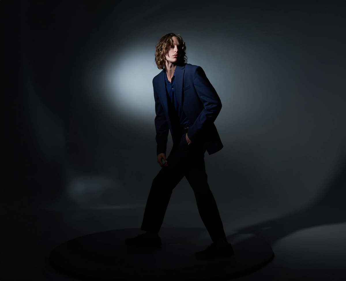 A vintage cinematic menswear scene -- structured tailoring, soft lighting, the language of the suit at its most expressive