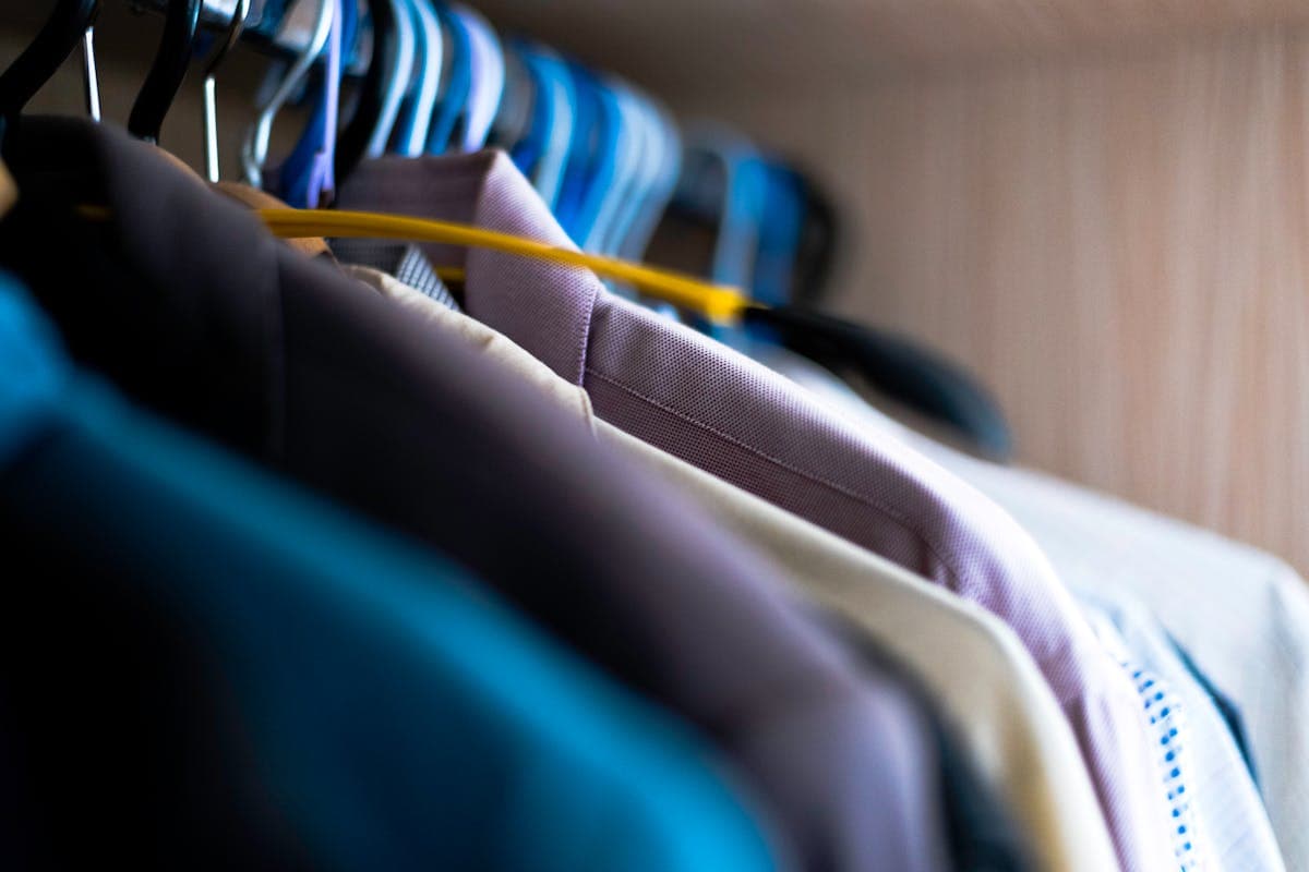 A row of finished custom suits in different fabrics and colors hanging on a tailor's rack