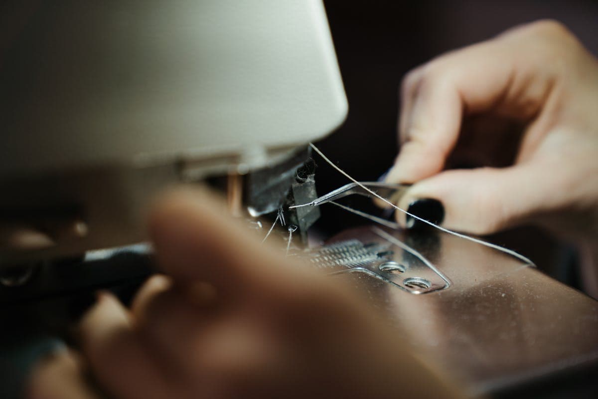 Close-up of a tailor's hands stitching a suit jacket lapel at a sewing machine