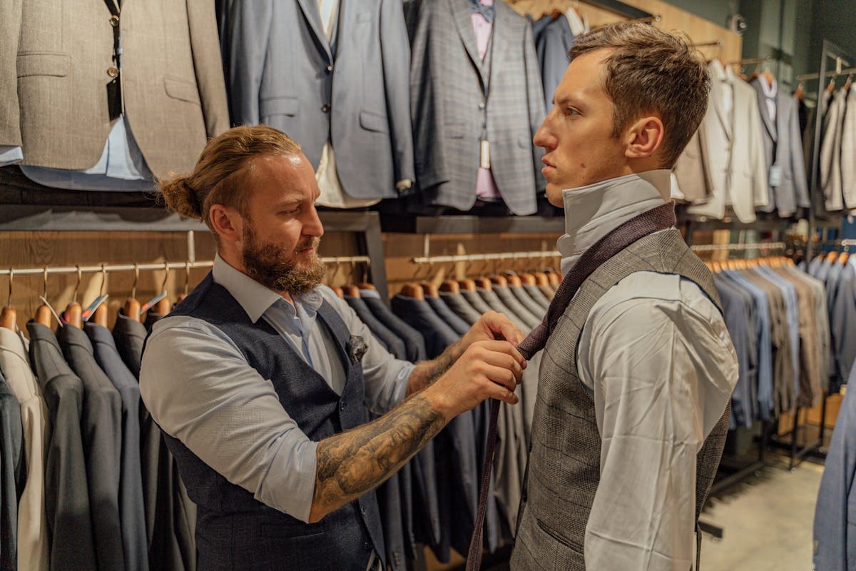 Row of finished tailored suit jackets hanging on a wooden rack in a workshop