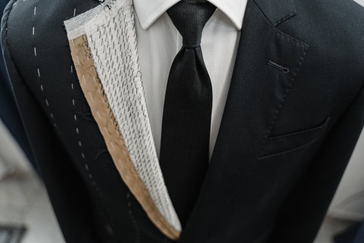 Tailor hand-stitching the interior canvas of a suit jacket at a workbench