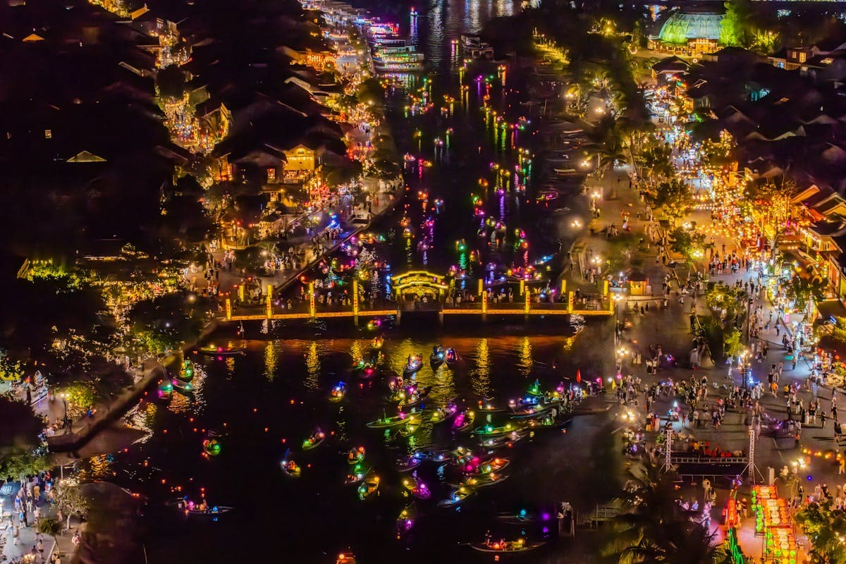 Silk lanterns glowing over the streets of Hoi An Old Town at night, reflected on the Thu Bon River