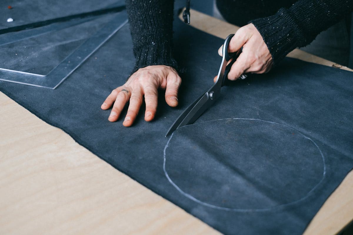 A tailor cutting fabric by hand for a made-to-measure dress in a workshop