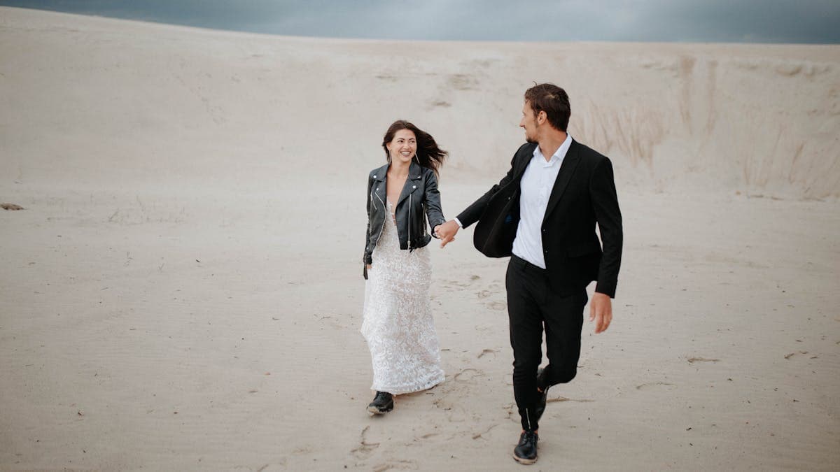 Couple in wedding attire walking through a desert landscape -- the convergence of festival fashion and destination weddings in 2026