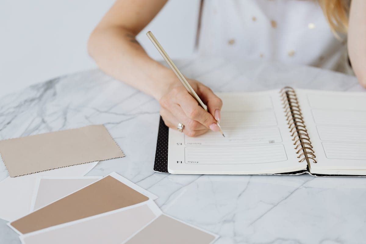 Wedding planning flatlay with a calendar, fabric swatches, color palette cards and a notebook laid out on a wooden table for a destination wedding