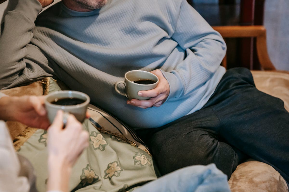 Relaxed engaged couple sitting together on a sofa taking a break from wedding planning