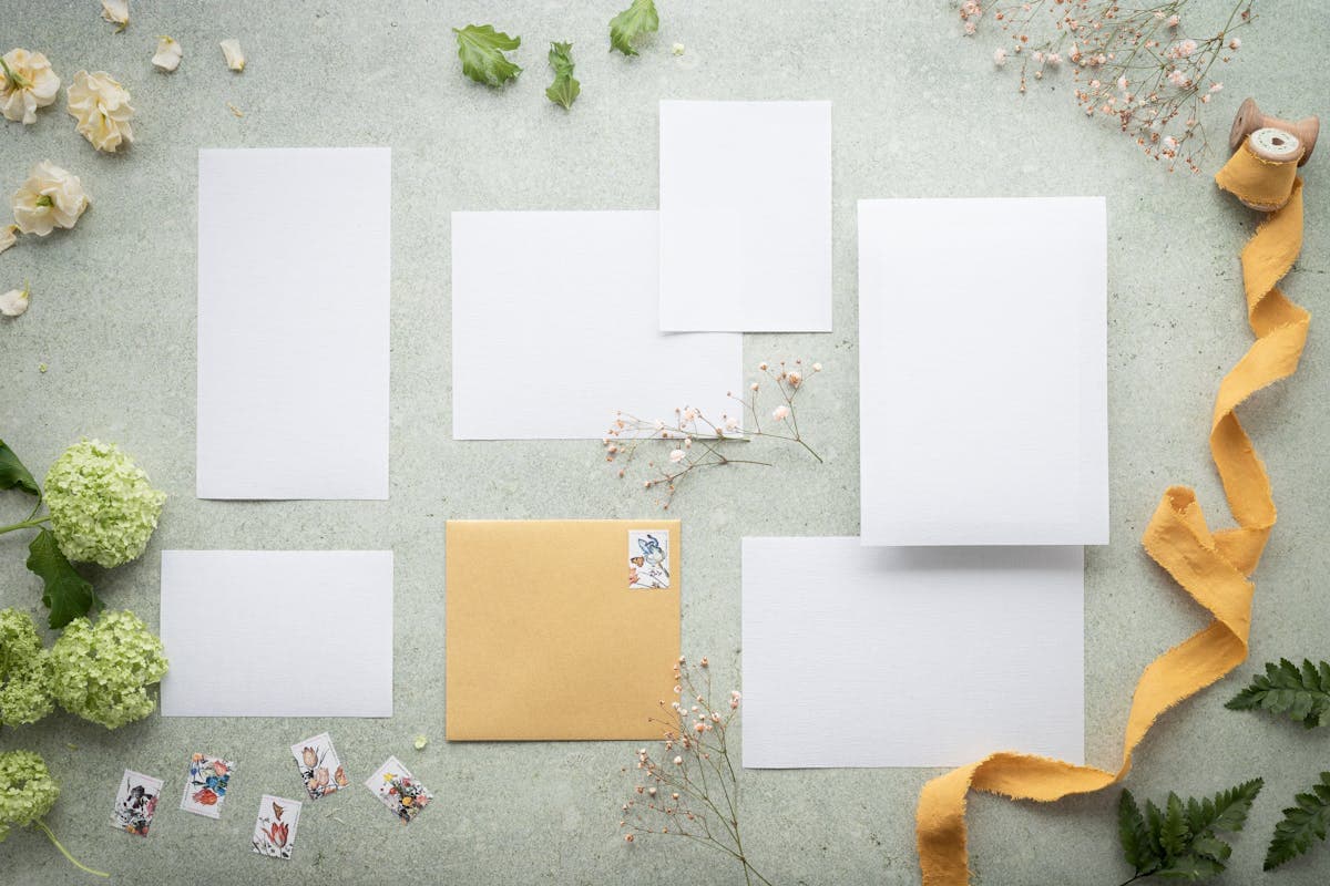 Flatlay of elegant wedding invitations, envelopes, and a fountain pen on a neutral background