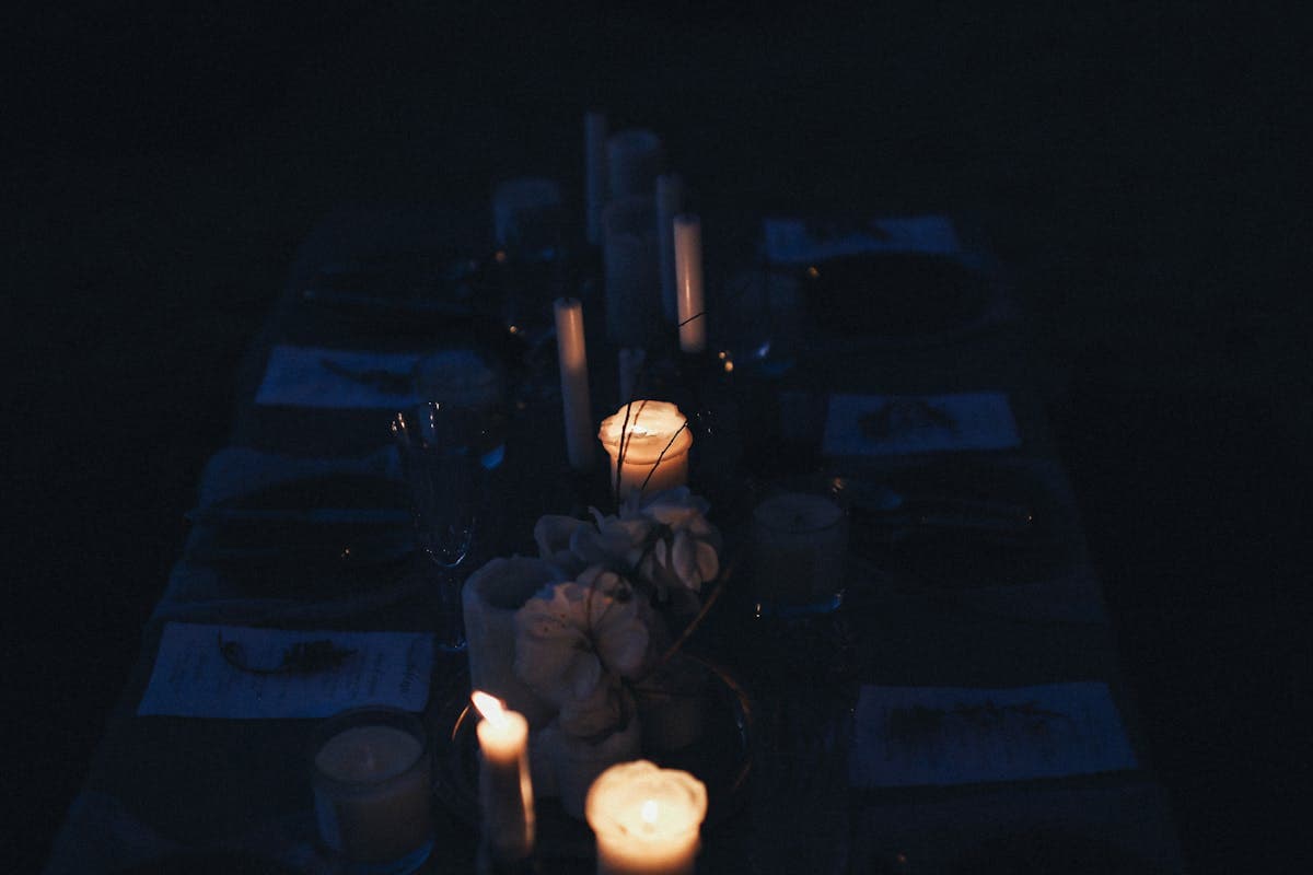 Warm candlelit winter wedding reception table with soft lighting and greenery in an intimate venue