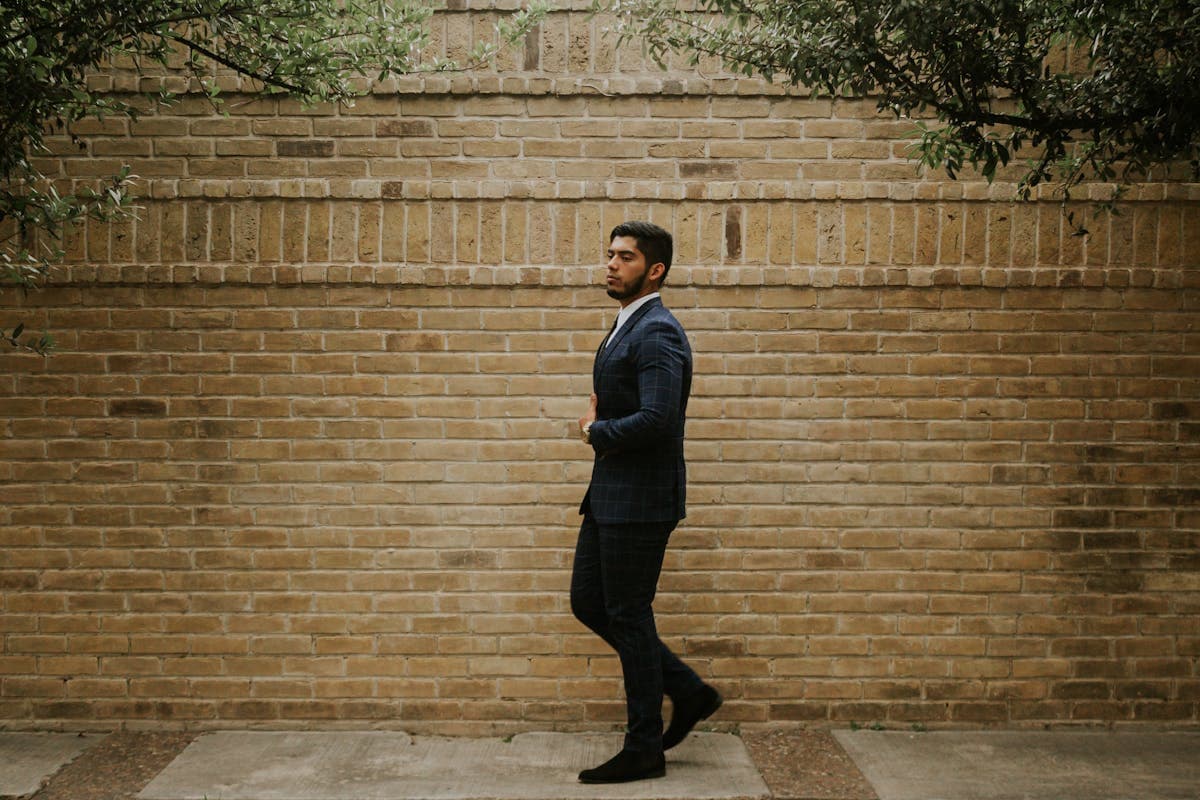 Young groom in a contemporary double-breasted suit with a clean shoulder line and tapered trousers, standing confidently in natural light