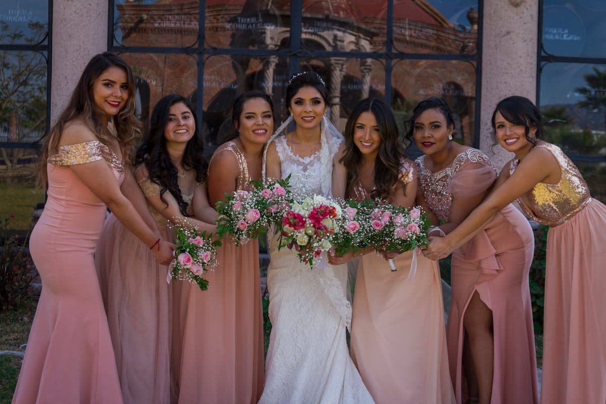Bridesmaids in identically color-matched dresses holding bouquets together
