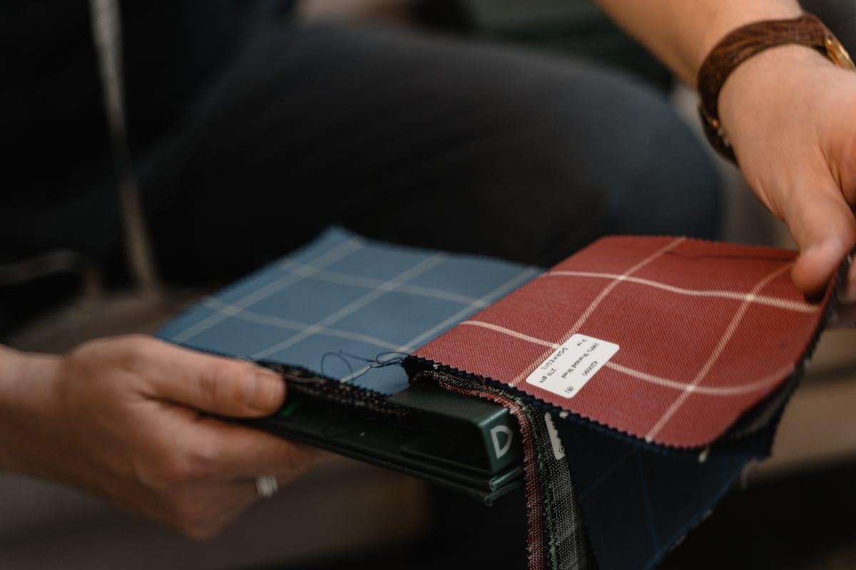 Hands comparing fabric swatches and color samples while choosing material for custom wedding attire