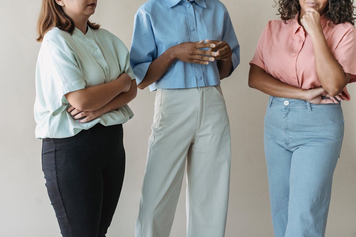Three or four well-dressed twenty-somethings in distinct muted tailored looks standing together, illustrating one shared vocabulary in different executions