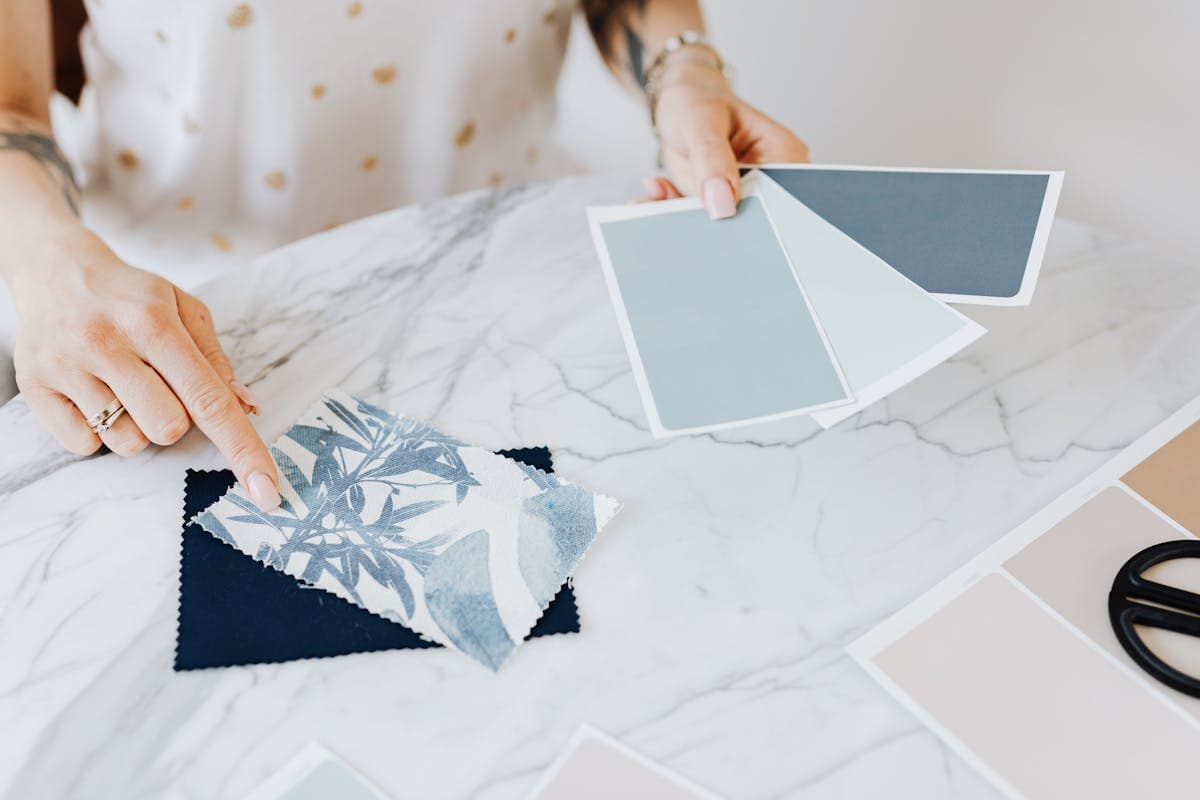 Young person examining and choosing from a stack of folded fabric swatches