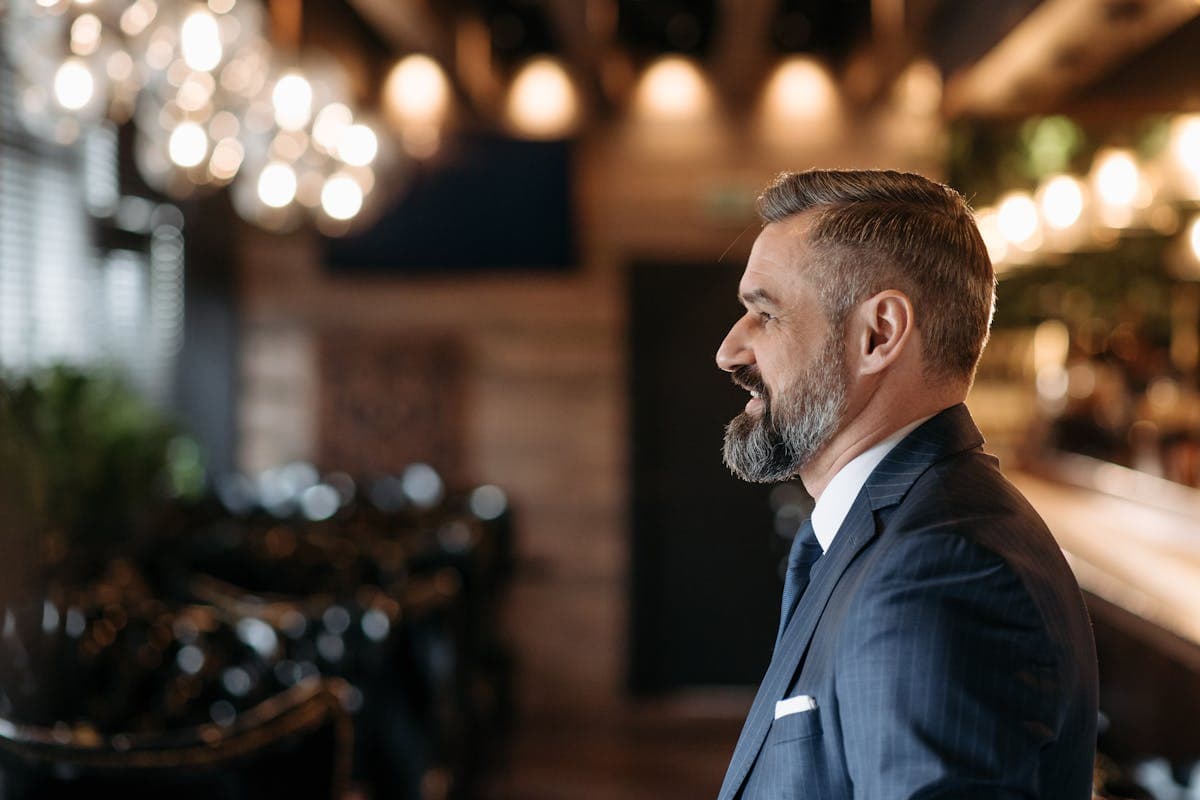 A confident mature man in a well-fitted navy suit standing relaxed, representing the different dads who each need a different cut and fabric
