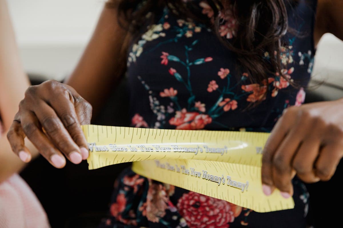 Parent measuring a child at home with a soft tape measure across the shoulders