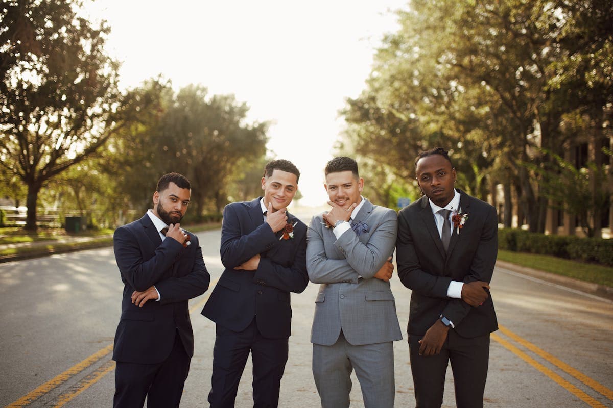 Group of men in tailored suits attending a celebration, smiling and standing together at an outdoor event