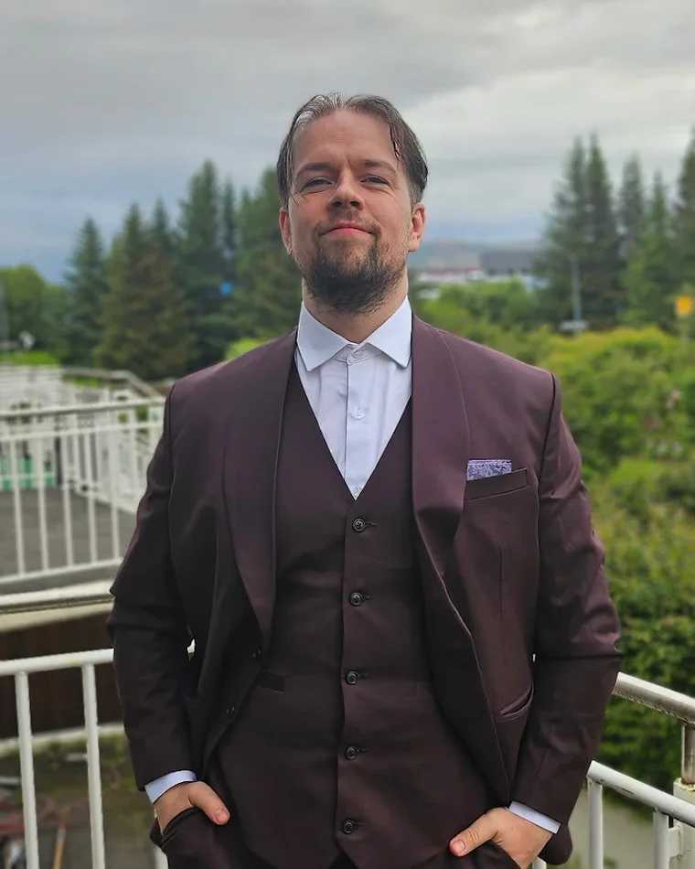 Daði in Reykjavík wearing his custom burgundy three-piece suit from Nathan Tailors — jacket, waistcoat, dress shirt and pocket square, cut to his measurements and shipped to Iceland
