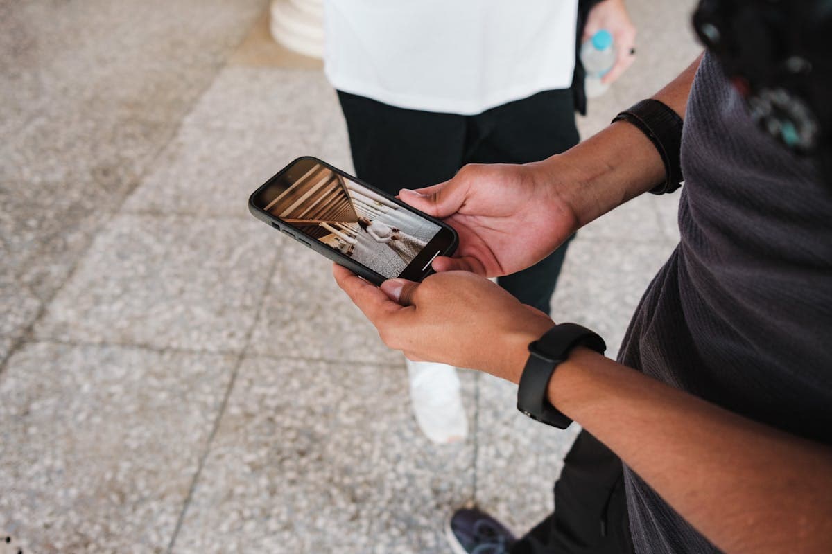 Hands holding a phone showing clothing style reference photos beside a notebook, prepping for a tailor visit