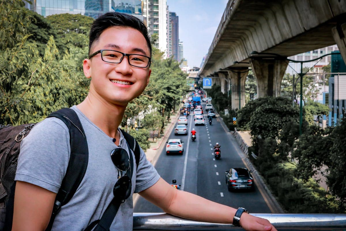 A solo traveler with a backpack on a warm Southeast Asian street, working from cafes with no fixed schedule