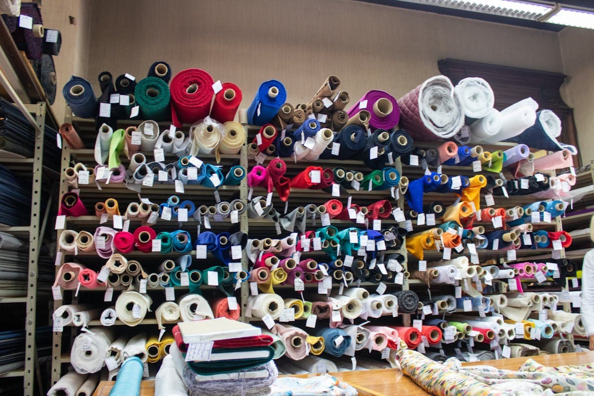 Shelves of rolled wool and wool-blend suiting fabric bolts in a range of colors at a tailor shop