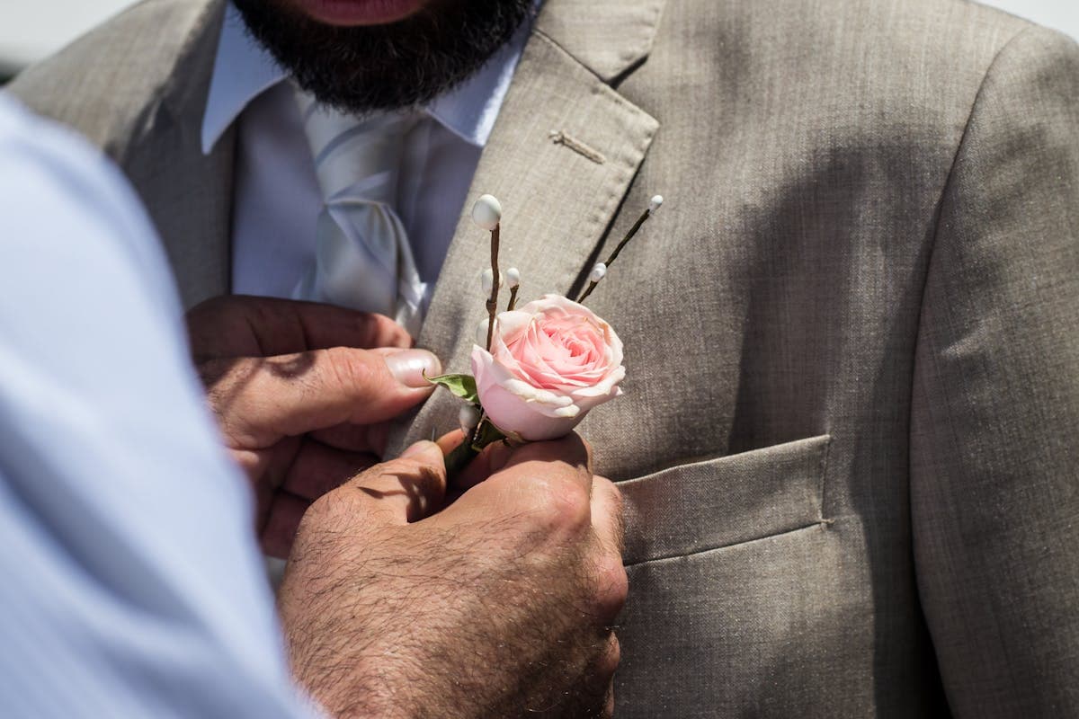 Close-up of a tailored suit lapel and buttonhole being adjusted by hand in a workshop.