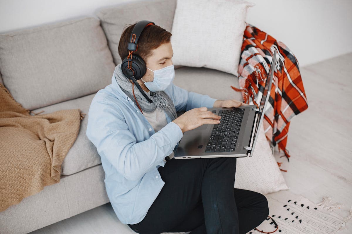 A man holding a tape measure while taking a video call on a laptop at home
