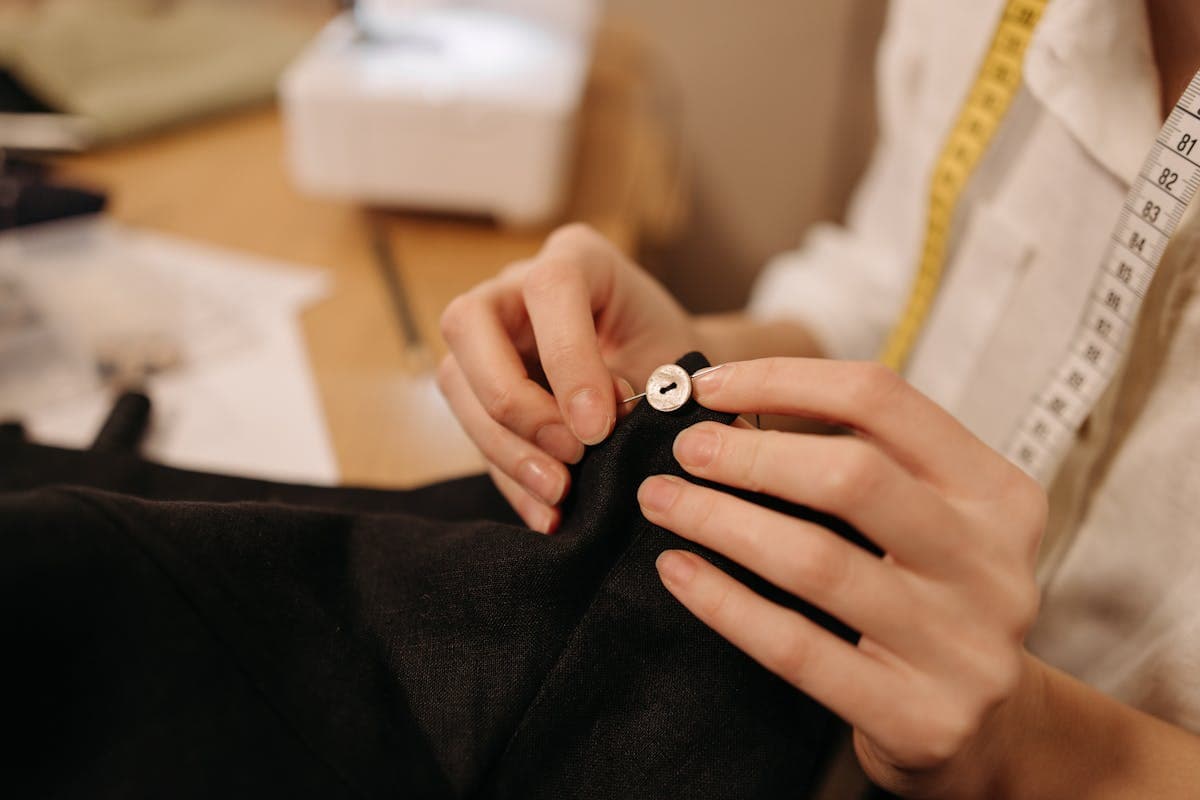 Close-up of a tailor's hands hand-stitching a jacket lapel at a sewing bench