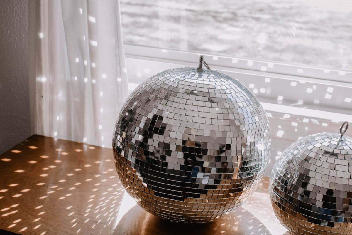 Retro 70s disco scene with a mirror ball and warm lighting, evoking the tailoring-driven disco revival of 2026