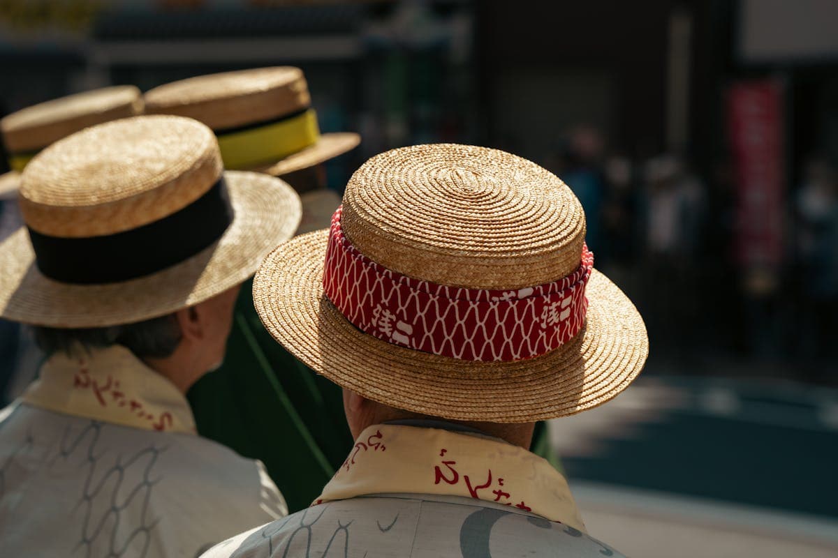 Two stylishly dressed men in summer-weight suits and boater hats standing together at an outdoor English summer event