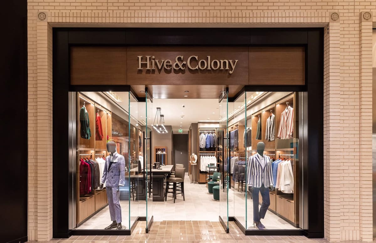 Hive & Colony showroom storefront with glass frontage, wood fixtures and suits displayed on mannequins