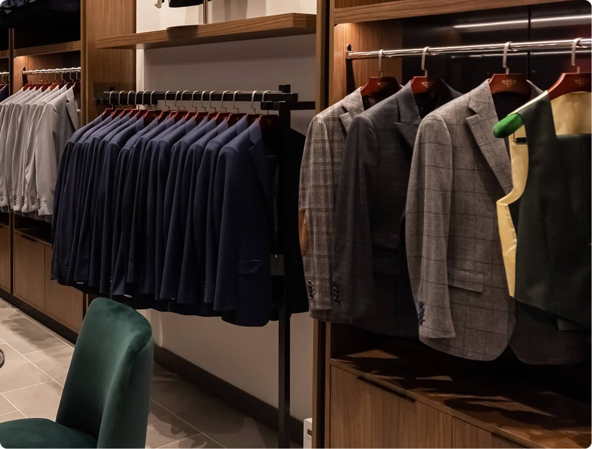 Interior of a Hive & Colony showroom with rails of navy and checked jackets under warm lighting