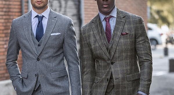Two men walking in tailored tweed suits, one grey birdseye and one brown windowpane check