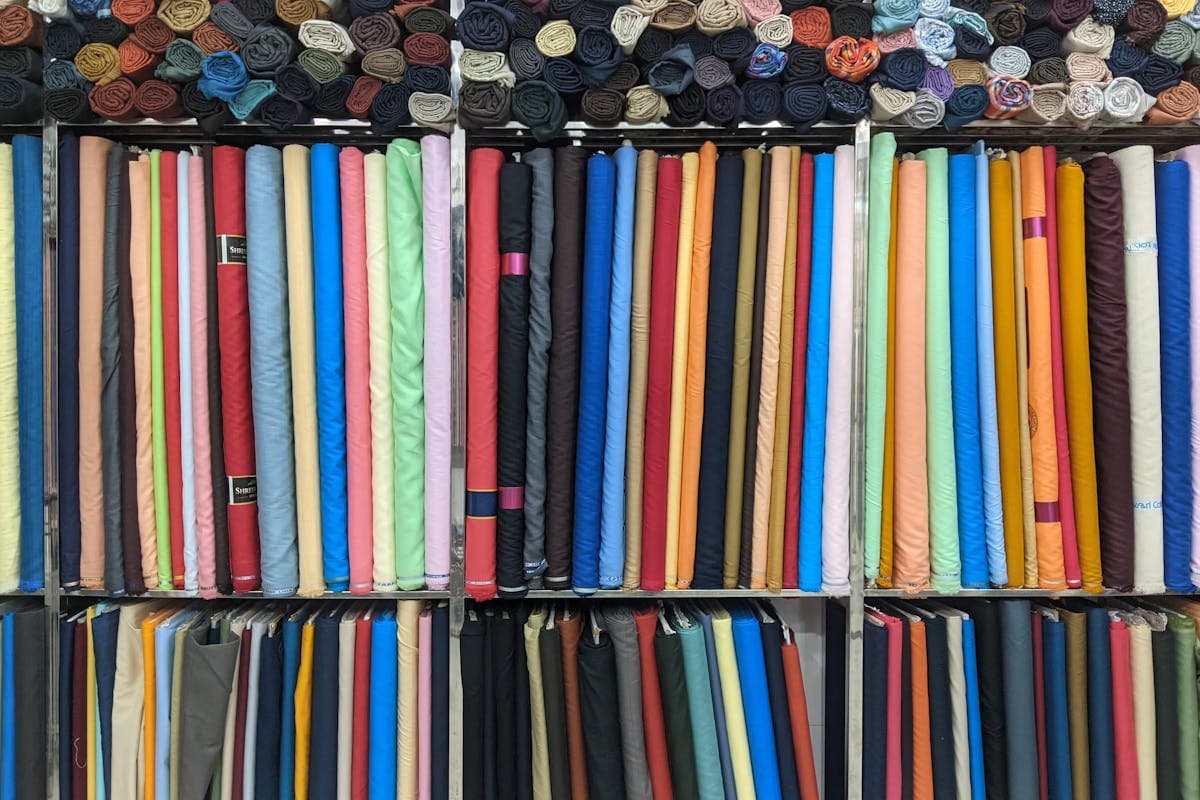 Stacked bolts of wool suiting fabric and colourful swatch cards on a tailor's table in Hoi An