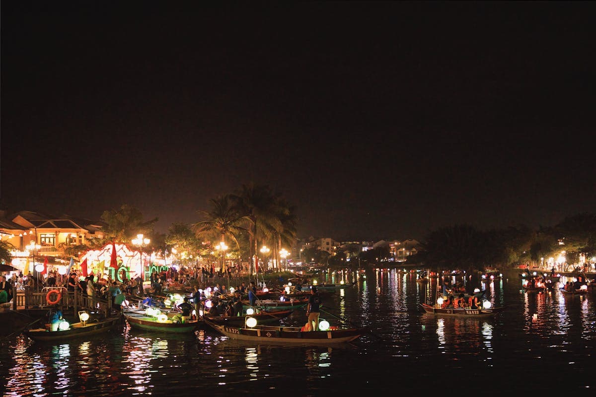 Silk lanterns glowing in every colour over the Thu Bon River in Hoi An at night with reflections on the water