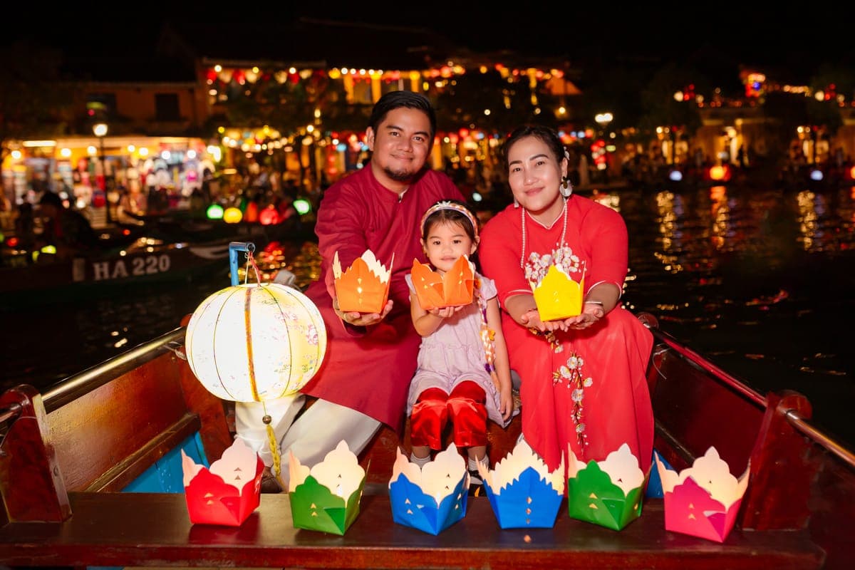 Hundreds of small floating paper candle lanterns drifting on the dark Thu Bon River at night in Hoi An